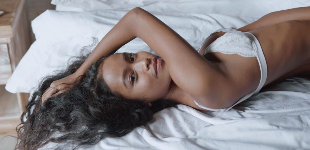 Woman lying in bed wearing a white bra